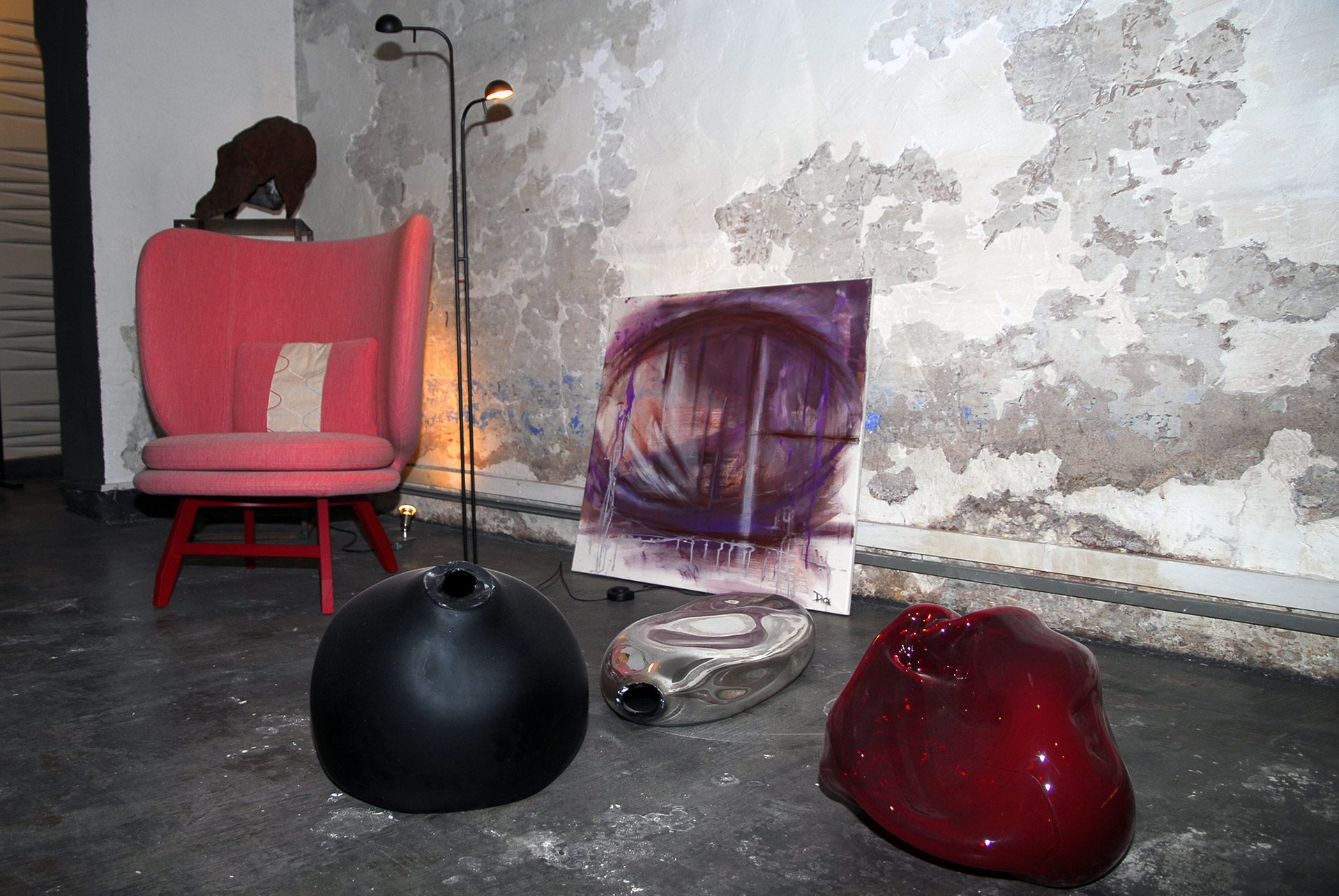 Poltrona rossa e quadri appoggiati a una parete dello showroom Bistolfi